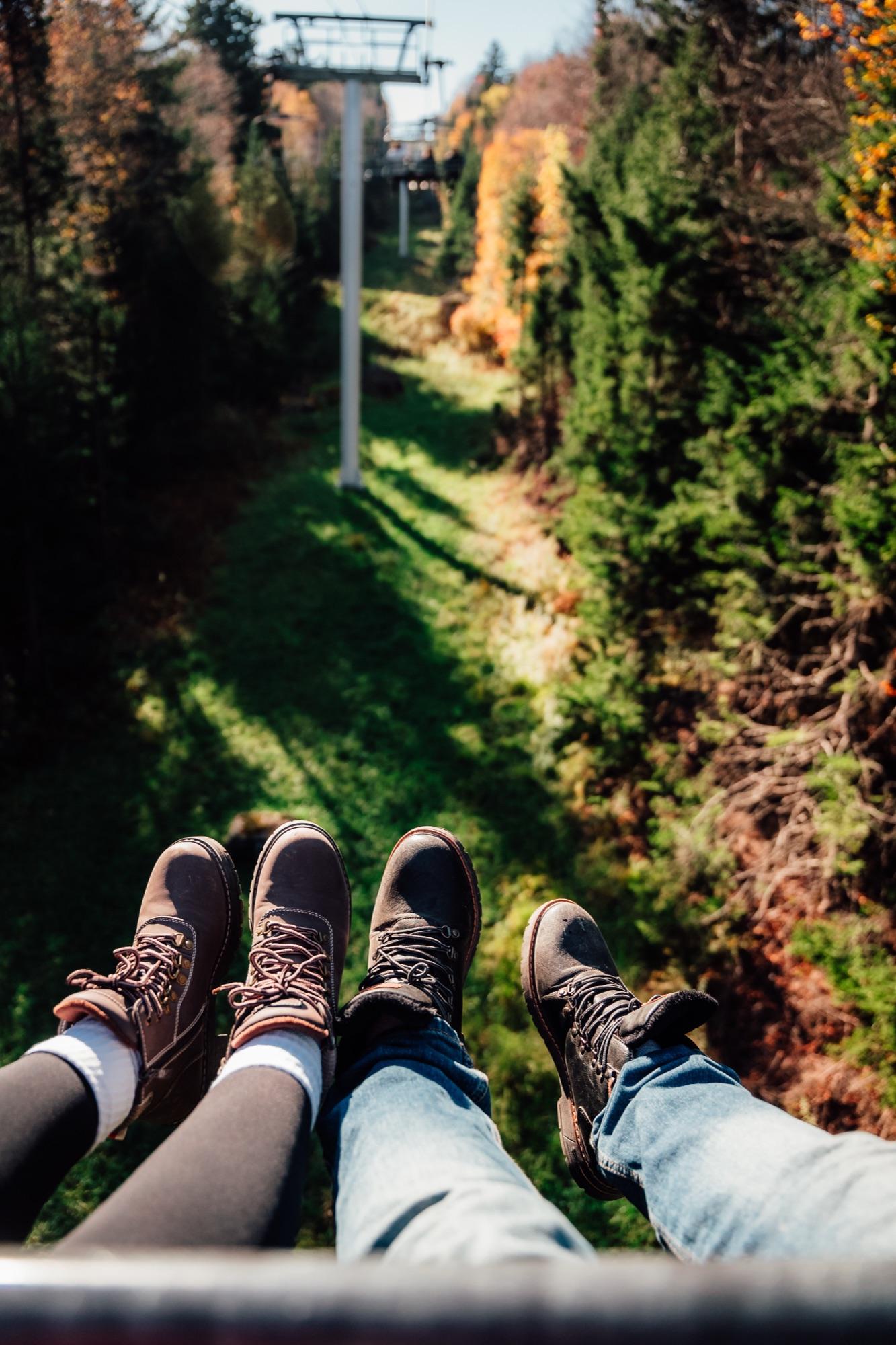 Boots dangling from the chairlift over a fall trail at Snowshoe