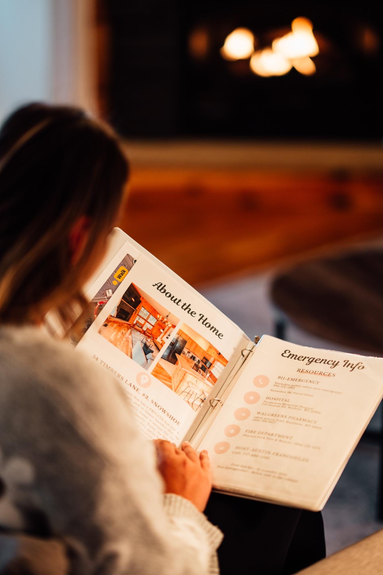 A guest reading the printed house guide by the fireplace in a Wander Luxe home