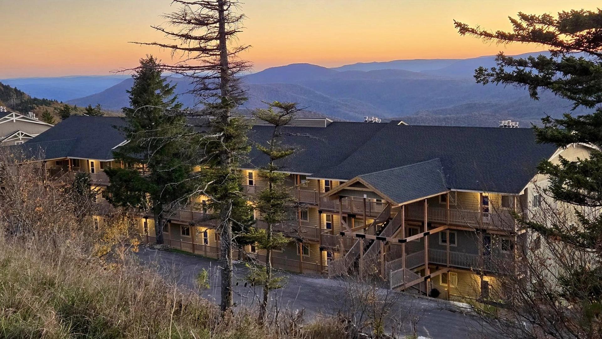 A Summit condo building at Snowshoe lit up at sunset with mountains behind it