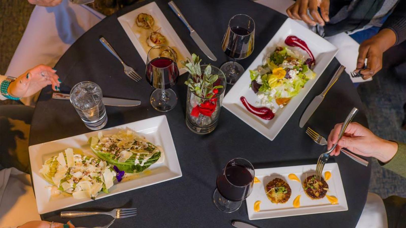 Small plates and glasses of red wine on a black tablecloth at 10 Prime in Soaring Eagle Lodge