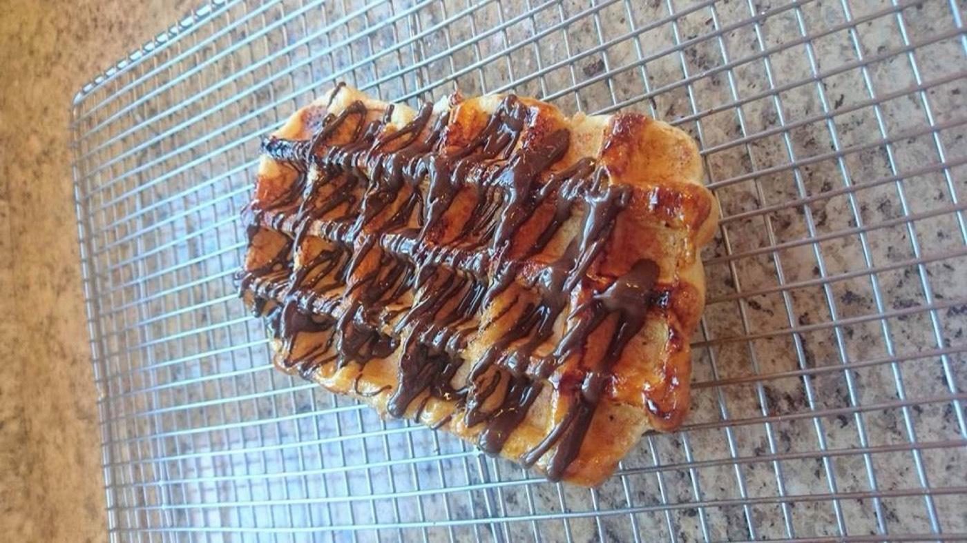 A fresh Waffle Cabin waffle drizzled with chocolate on a cooling rack