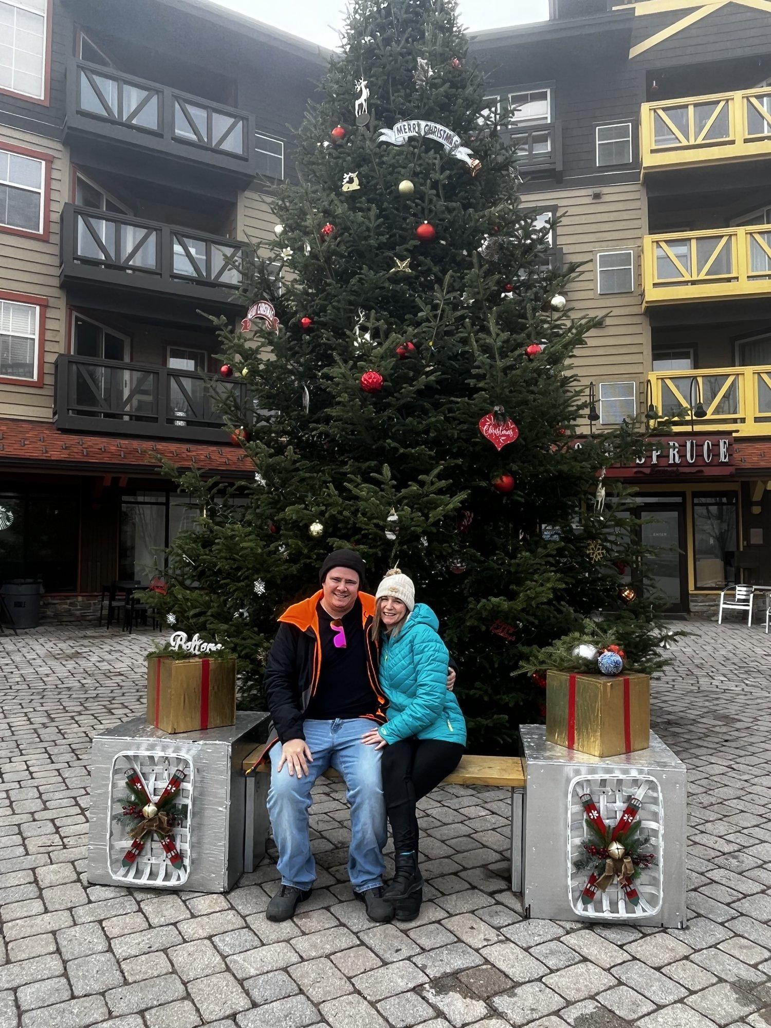 Two guests beside the Village Christmas tree at Snowshoe