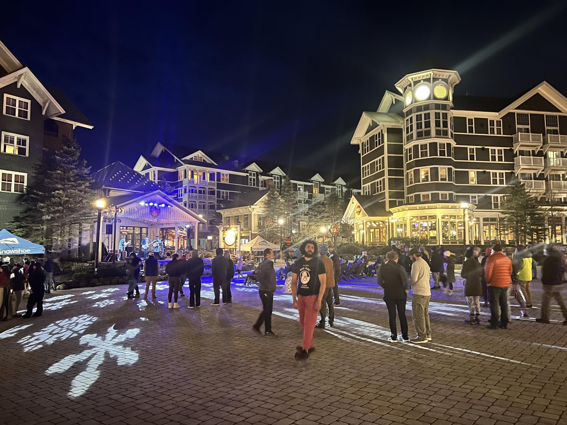 The Village at Snowshoe lit up at night with a crowd on the walkway